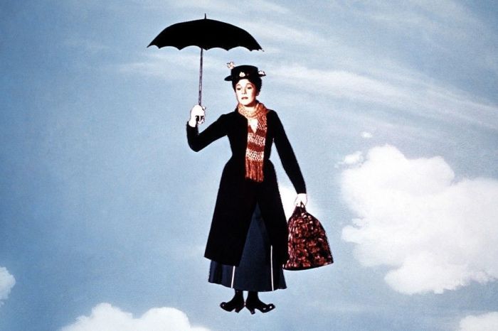 Julie Andrews, segurando uma sombrinha e uma bolsa, em cena do filme 'Mary Poppins', de 1964. Atrás, algumas nuvens e o azul do céu
