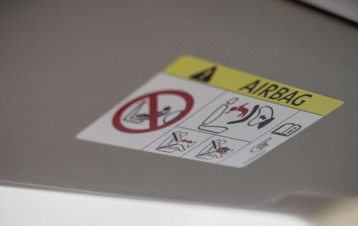 Este adesivo preso no para-sol aponta os riscos do airbag e determina a consulta ao manual