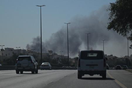 Motoristas trafegam por uma rua enquanto fumaça sobe de um suposto ataque iraniano na área onde fica a Embaixada dos EUA na Cidade do Kuwait, em 2 de março de 2026