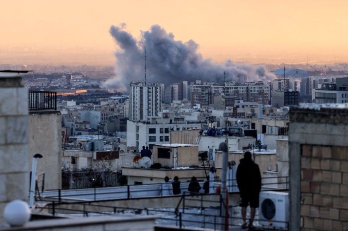 Uma pessoa observa, do telhado de um prédio, uma coluna de fumaça que se eleva após um ataque à capital iraniana, Teerã, em 3 de março de 2026