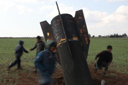 Grupo de crianças brincam em torno de míssil que caiu em área descampada na Síria