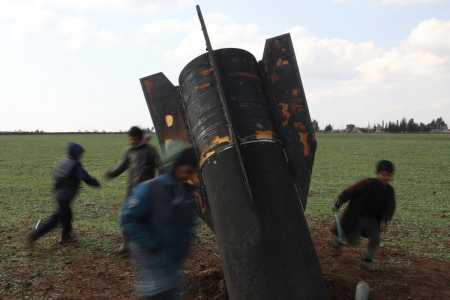 Grupo de crianças brincam em torno de míssil que caiu em área descampada na Síria