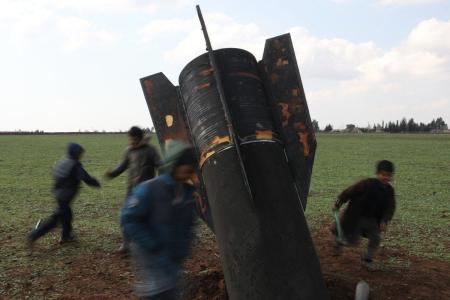 Grupo de crianças brincam em torno de míssil que caiu em área descampada na Síria