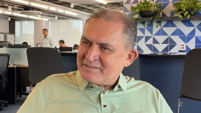 homem de camisa verde em escritório com paredes azuis e brancas 