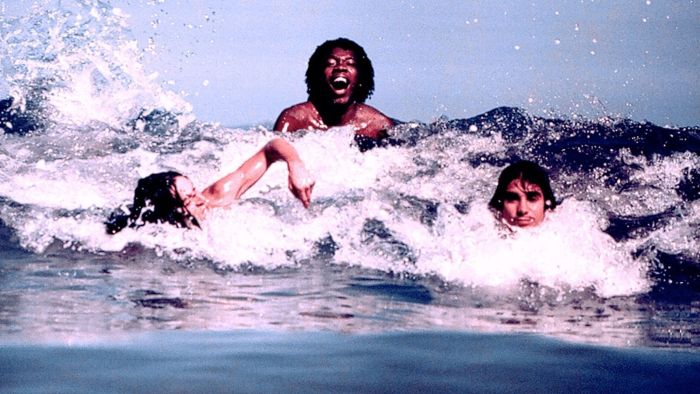 Foto mostra Beto Guedes, Milton Nascimento e Lô Borges nadando em uma praia de Niterói, no Rio de Janeiro