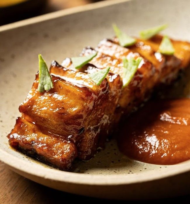 Barriga glaceada com rapa de angu crocante, tutu cremoso, purê de abóbora, molho gavião, hortelã-pimenta e vinagrete de milho verde