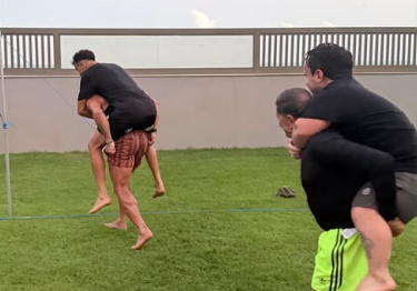 Hulk e Gilvan carregando Reinier e Juquinha após o desafio de futevôlei