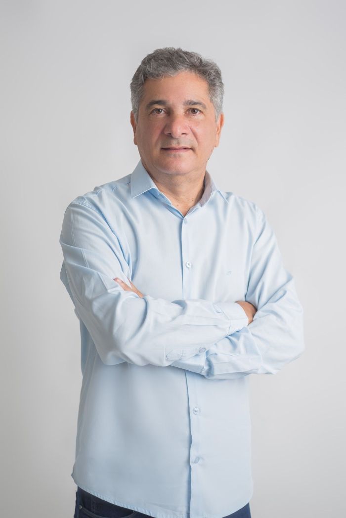 Coronel Sandro é um homem branco, usa uma camisa social azul clara e cabelos brancos.