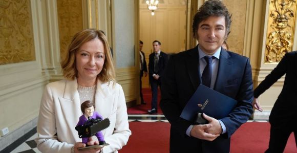 Meloni, primeira-ministra da Itália, segurando boneco ao lado de Javier Milei