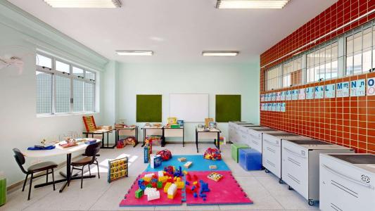 sala de aula, com mesas cadeira e objetos lúdicos
