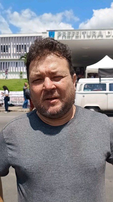 Gustavo Olímpio é um homem branco, com cabelo castanho e barba branca. Na imagem, ele usa uma camisa cinza.