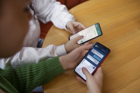 Duas pessoas seguram celulares enquanto mexem no WhatsApp