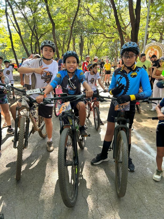 Crianças que participaram do evento puderam competir e participar de atividades Imagem mostra três crianças com três bicicletas sorrindo para foto