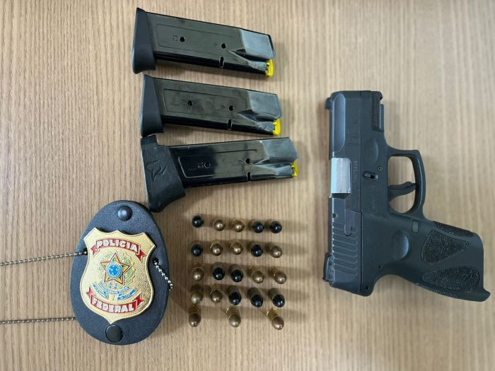 Imagem mostra arma de fogo apreendida pela Polícia Federal com alguns cartuchos ao lado 
