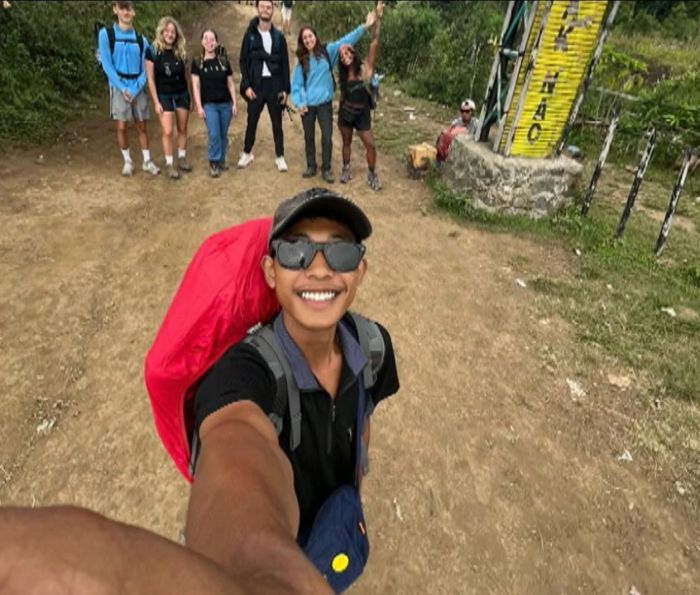 Na imagem aparece o guia no qual tira a foto e Juliana Marins aparece ao fundo, de roupa preta do lado direito.