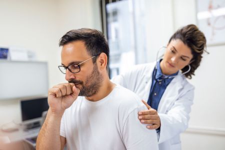 A female doctor at the clinic performs auscultation of the lungs of a patient with symptoms of coronavirus or pneumonia.