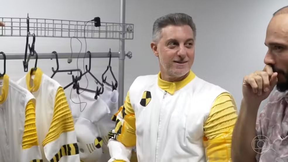 Luciano Huck ‘invade’ a casa do BBB 26 fantasiado de Dummy e revela bastidores do reality