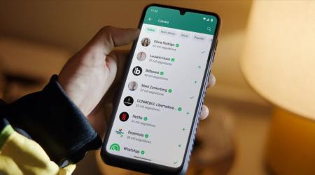 Pessoa segura um celular com a tela acessa e ligado na aba "Canais" do WhatsApp