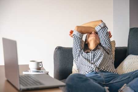 Mulher cansada do trabalho home office em frente a um laptop