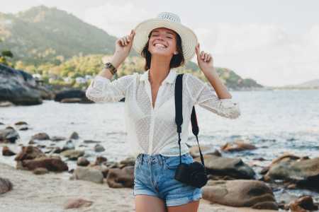 Mulher viajando e sorrindo para uma foto na praia