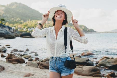 Mulher viajando e sorrindo para uma foto na praia