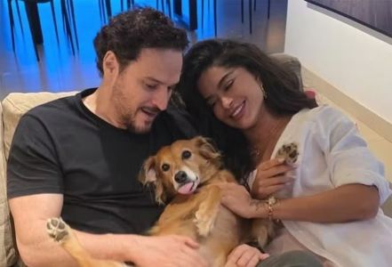 Casal deitado no sofá com vachorro vira lata caramelo