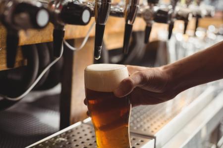 Close-up de uma pessoa completando um copo de cerveja em uma máquina