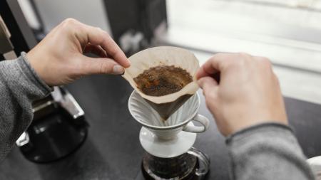 Foto de ângulo alto de barista retirando um filtro de café após preparo