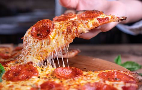 Pessoa branca pegando um pedaço de pizza