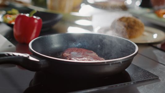 Close-up em carne bovina cozida em óleo em uma frigideira no fogão, no vapor e assando. Delicioso bife frito defumado, preparo de prato profissional