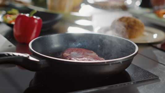 Close-up em carne bovina cozida em óleo em uma frigideira no fogão, no vapor e assando. Delicioso bife frito defumado, preparo de prato profissional