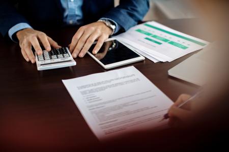 Mãos de homens assinando contrato e fazendo contas, discutindo sobre duplicatas escriturais