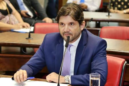 André do Prado é um homem branco, veste terno azul escuro com camisa branca e gravata lilás.