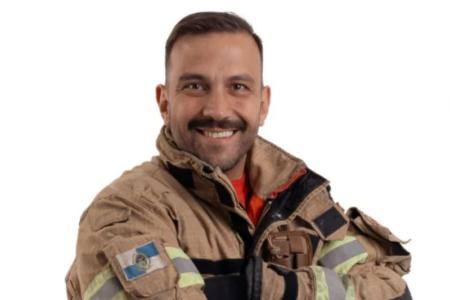 Rafael Luz é um branco com barba, bigode, cabelo raspado com roupa de bombeiro militar em um fundo branco