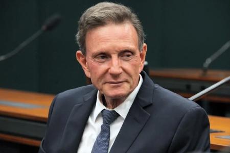 Marcelo Crivella é um homem branco e veste terno preto, camisa branca e gravata azul