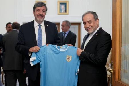Abbas Araqchi sendo presenteado por embaixador com a camisa da Seleção do Uruguai • Divulgação / Redes Sociais