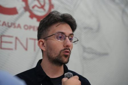 Luan Monteiro é um homem branco com cabelos morenos, barba e utiliza óculos