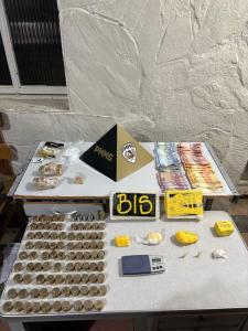 Polícia apreendeu duas barras de substância semelhante à cocaína, cocoína fracionadas para comercialização, porções de crack, uma balança de precisão, materiais utilizados para embalar entorpecentes, anotações relacionadas à possível venda de drogas e uma quantia em dinheiro.