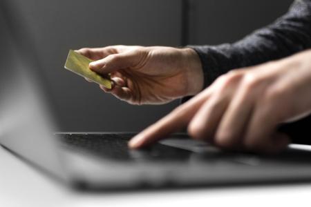 Pessoa utiliza o notebook para digitar dados bancários do cartão com segurança.