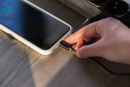 Conectando um cabo magnético a um smartphone para carregamento, em close-up