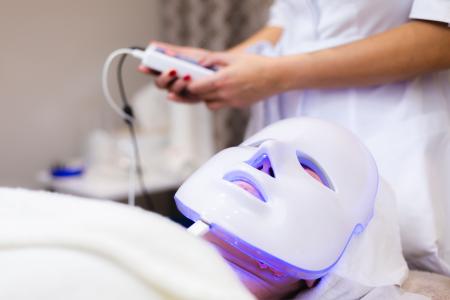 The client lies in the salon on the cosmetology table with a white mask on her face
