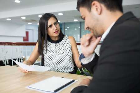 Empresária insatisfeita conversando com colega no escritório.