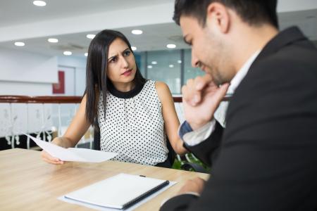 Empresária insatisfeita conversando com colega no escritório.