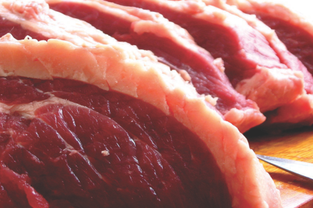 Peças de carne bovina crua com camada de gordura sobre uma superfície de corte. A imagem ilustra pesquisa que desenvolveu uma técnica para identificar espécies e raças de carne por espectrometria de massas.