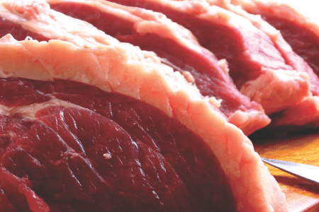 Peças de carne bovina crua com camada de gordura sobre uma superfície de corte. A imagem ilustra pesquisa que desenvolveu uma técnica para identificar espécies e raças de carne por espectrometria de massas.