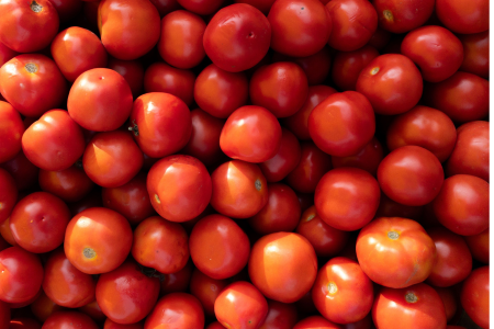 Tomates vermelhos empilhados em caixa de comercialização, representando o aumento da oferta do produto nas Ceasas e a queda dos preços registrada em junho.