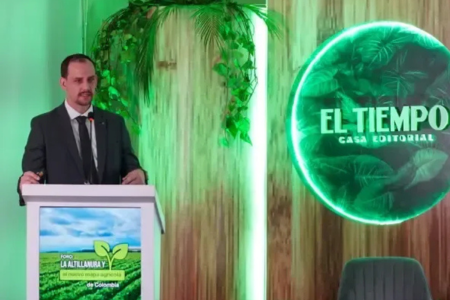 Cleiton Gauer faz apresentação em fórum internacional na Colômbia, em palco com púlpito e painel do evento, durante palestra sobre o modelo agropecuário de Mato Grosso.