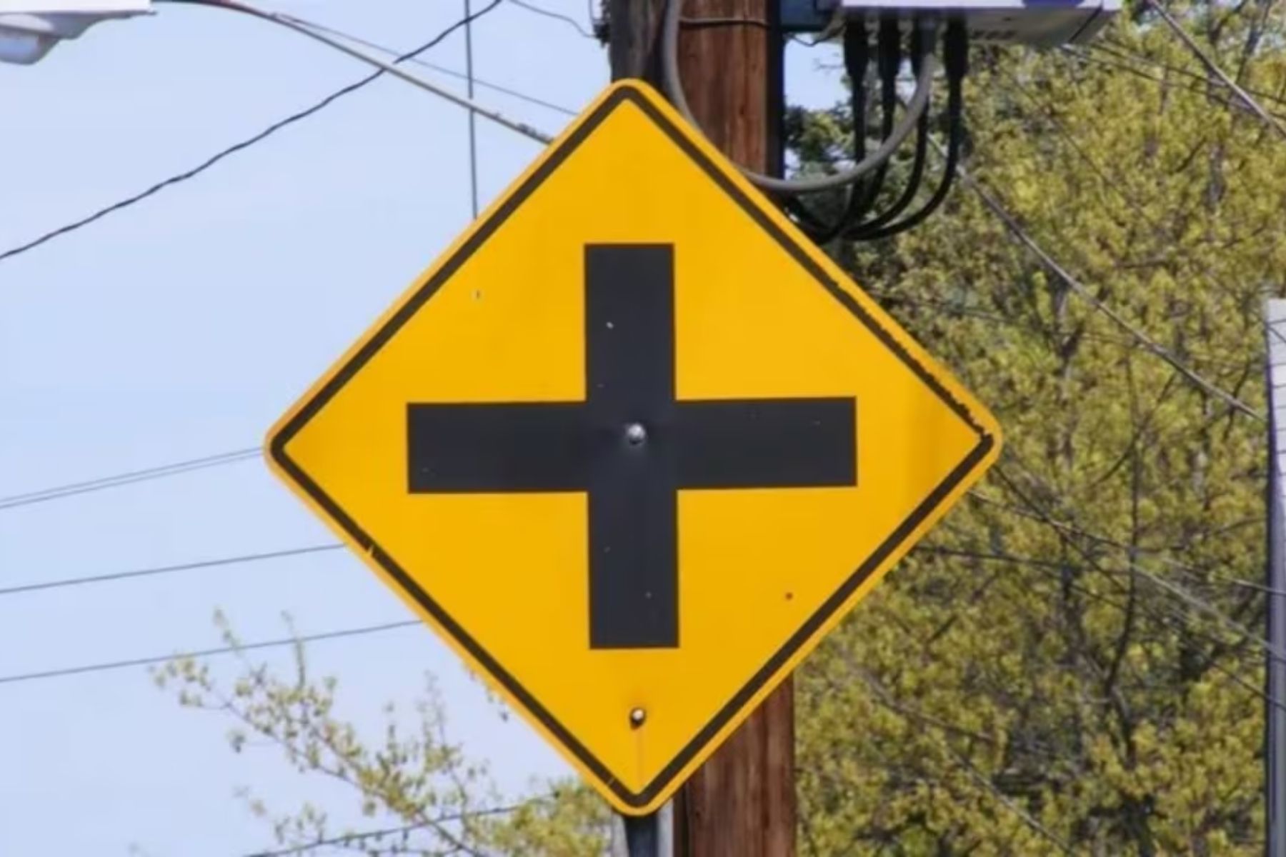 O que significa a placa de cruz preta em fundo amarelo no trânsito