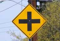 O que significa a placa de cruz preta em fundo amarelo no trânsito