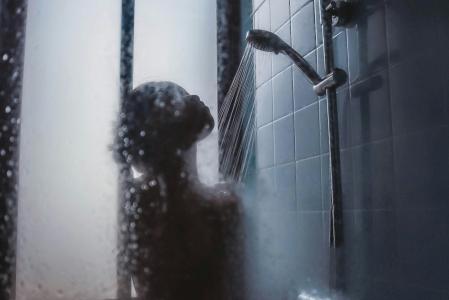 Mulher tomando banho quente com o box embaçado